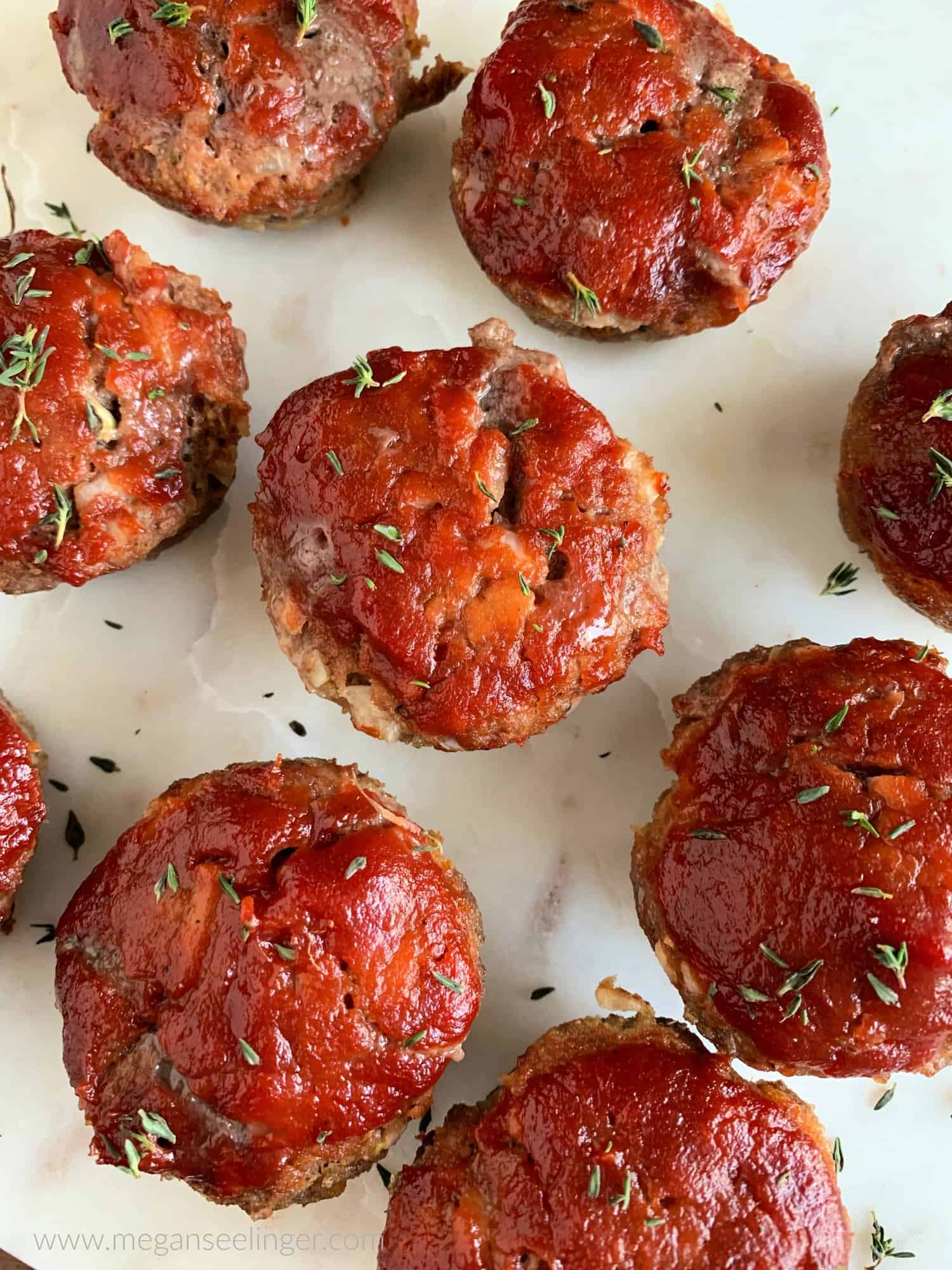 Keto meatloaf minis with ground beef on a white surface.