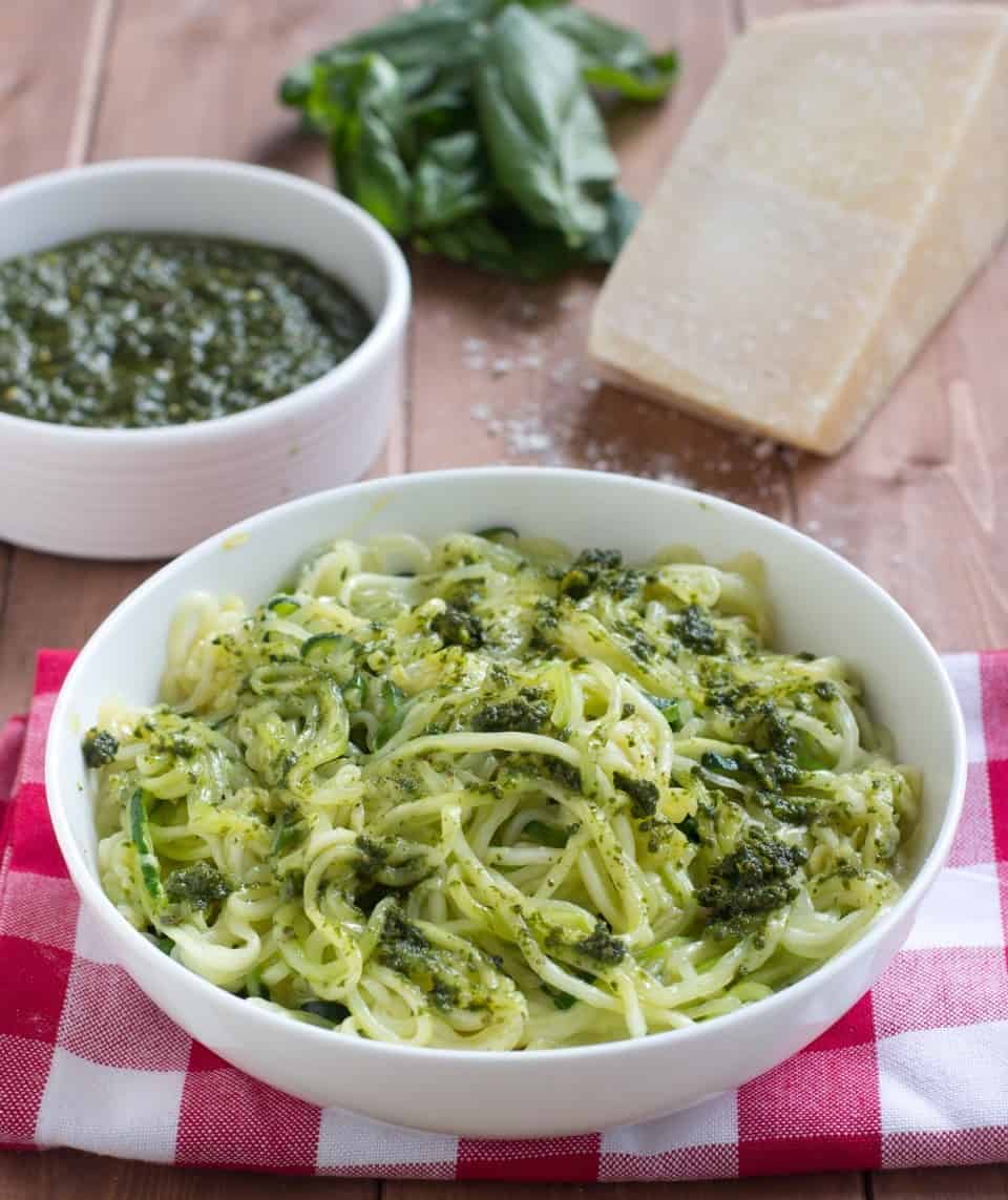 A bowl of pesto zoodles on a red checkered table.