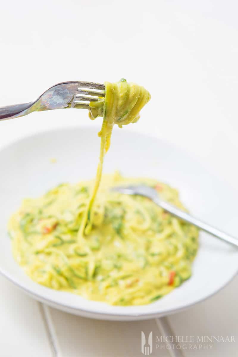 Creamy curried courgette noodles on a white plate.