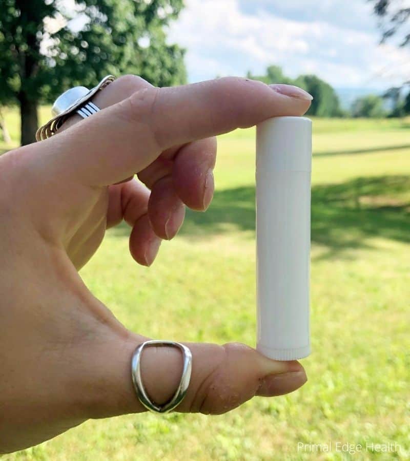 A hand holding a bottle of lip balm.