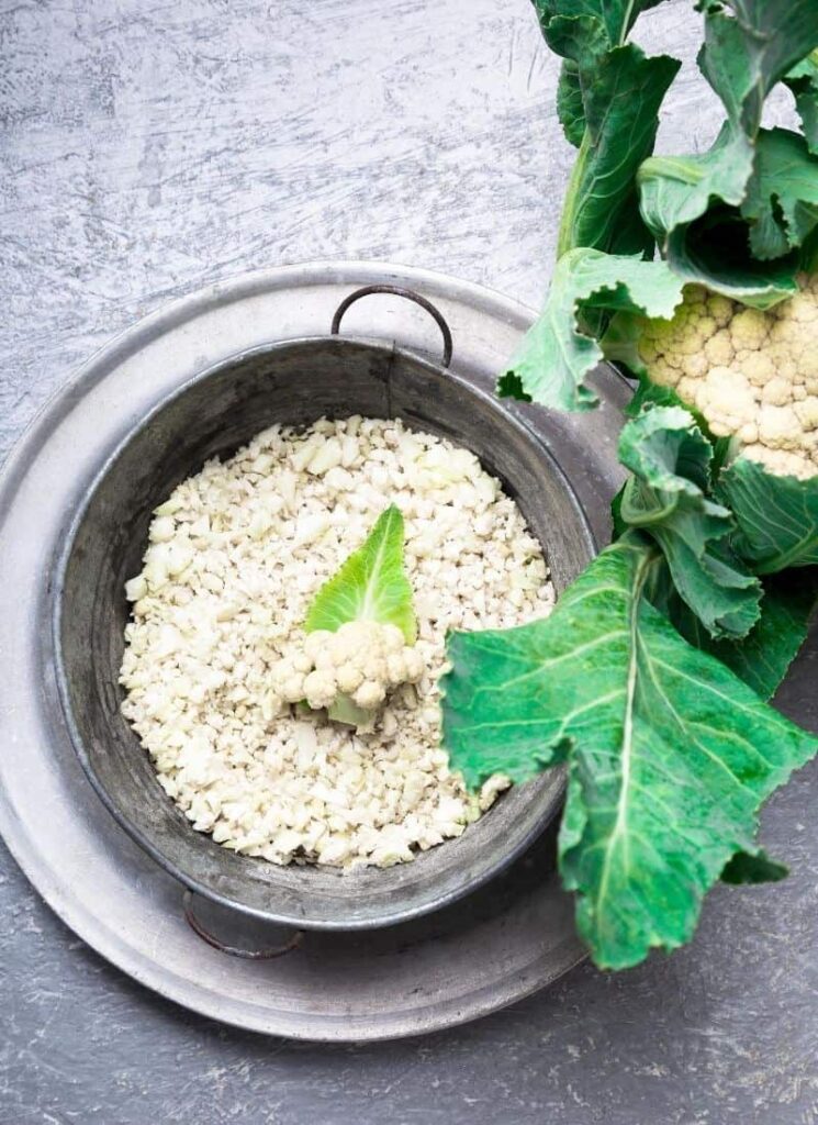 A picture of uncooked riced cauliflower in strainer.