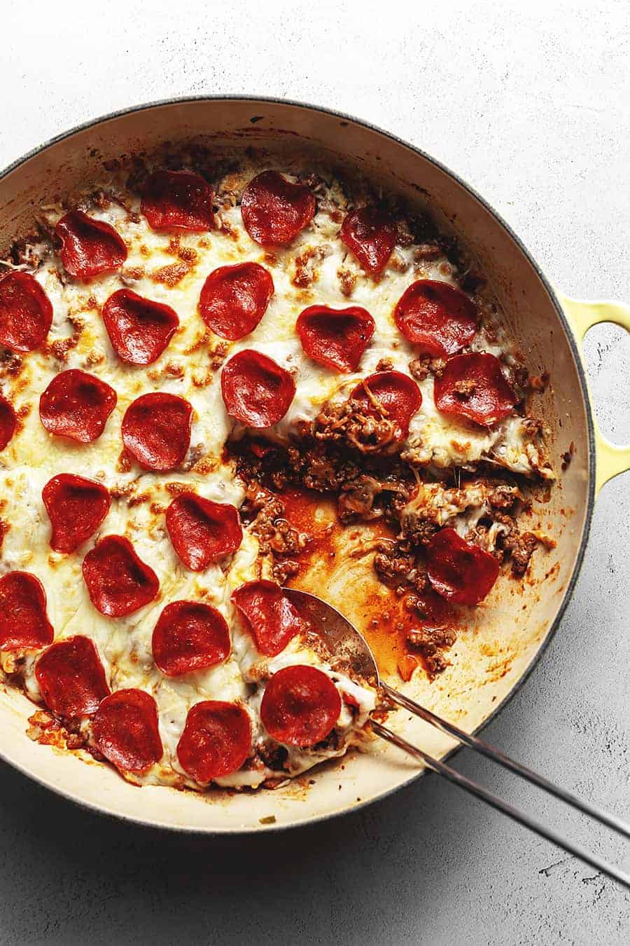 Keto pepperoni skillet pizza with ground beef on a white surface.