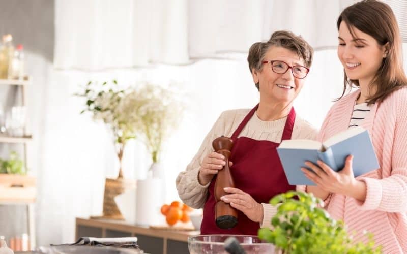 Two women in a kitchen reading a book about the Low Oxalate Diet.