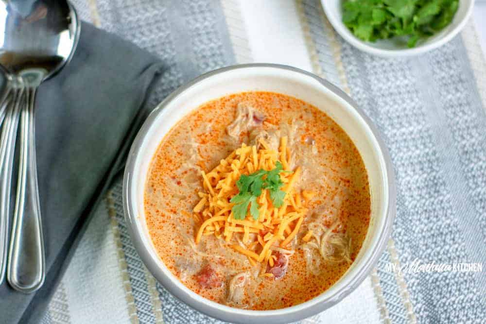 A bowl of low-carb chicken taco soup next to a spoon.