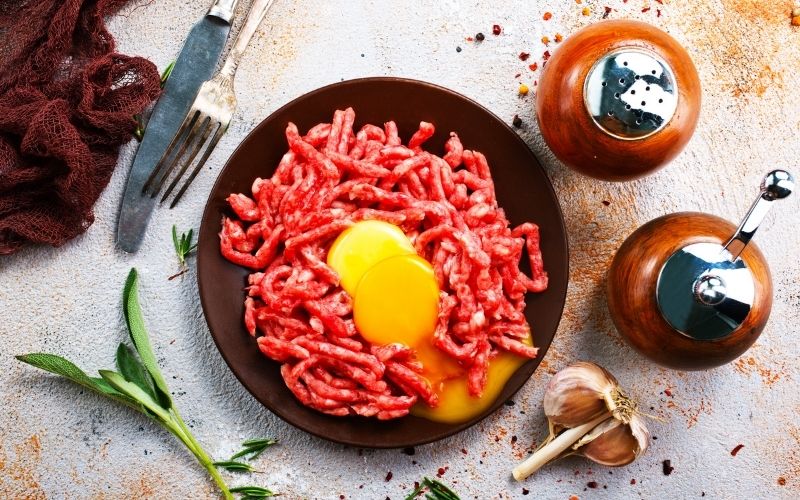 Ground beef and egg yolks on a brown plate.