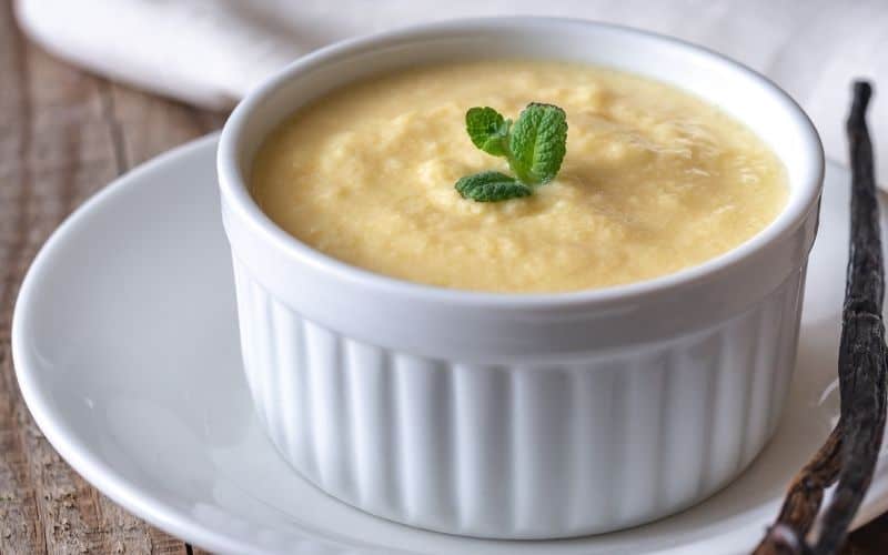 Yellow sauce in a white small bowl on top of a white plate.