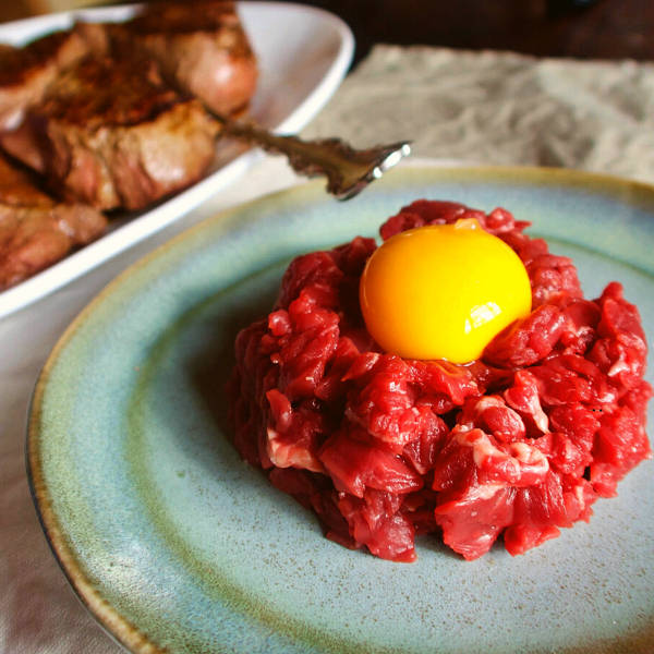 Steak tartare with egg yolk on blue plate.