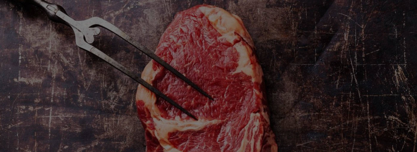 A piece of steak on a brown surface.