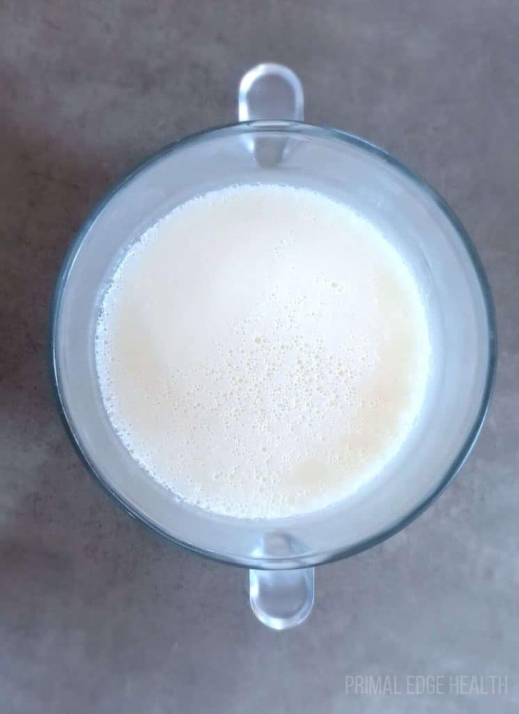 A clear container halfway filled with white liquid.
