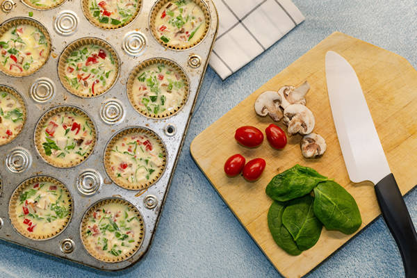 A recipe being prepped in a baking tray with wooden cutting board on the side.