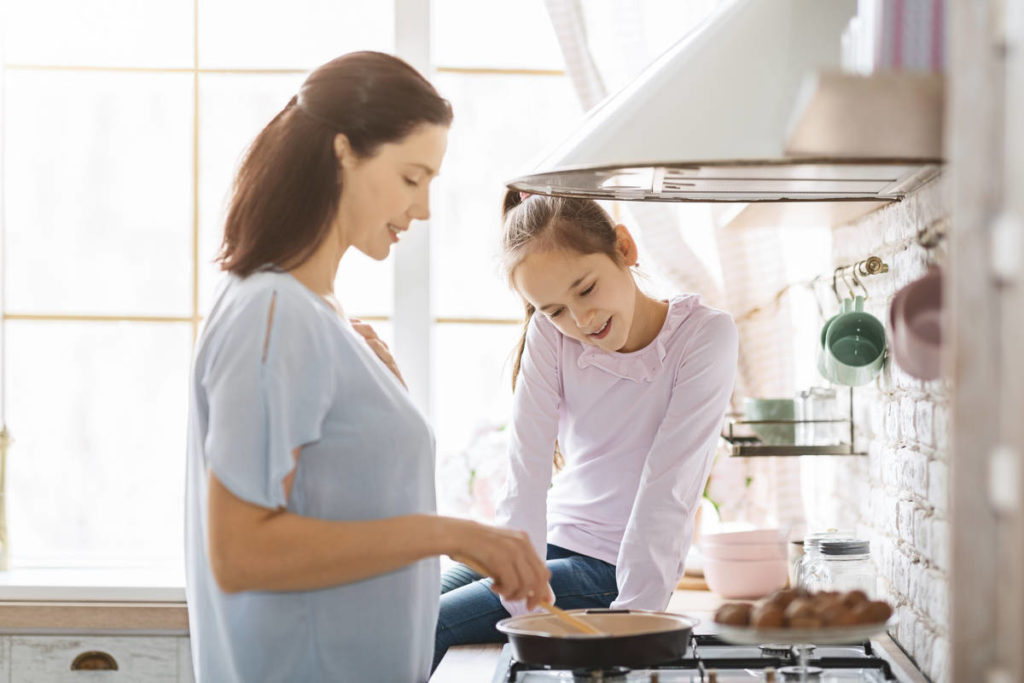 A woman and a child preparing food in the kitchen.