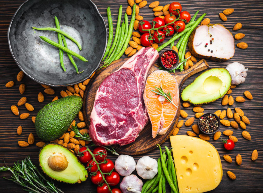 Various meat and vegetables on a wooden surface.