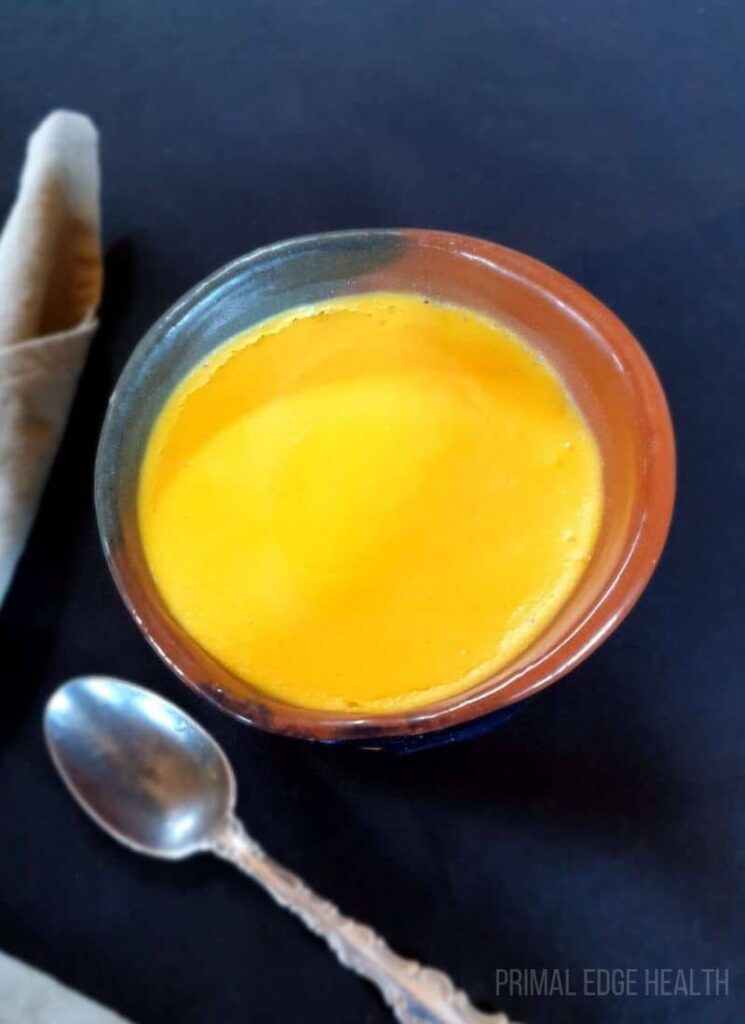 A bowl of egg pudding served with a spoon.