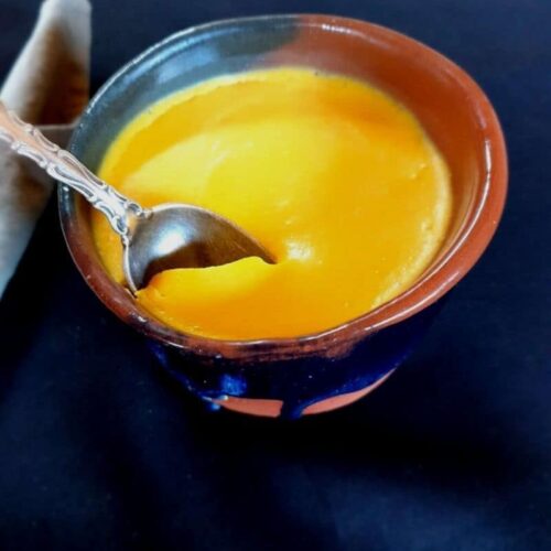 Egg pudding in a small bowl on a blue surface.