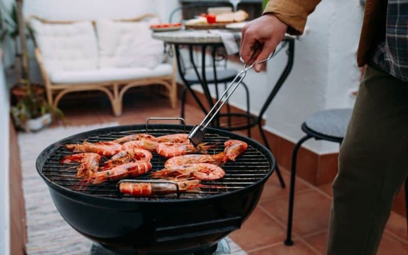 A person grilling shrimps.
