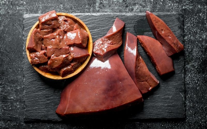 Raw meat on a black surface.