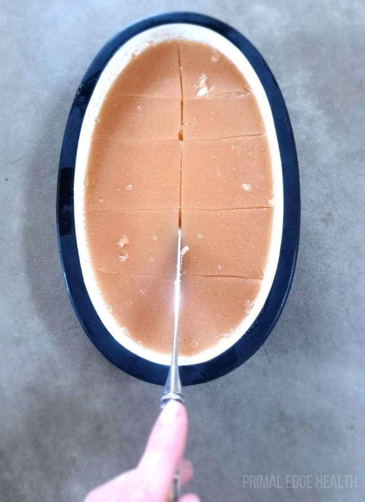 Keto gelatin in a dish being sliced with a knife.