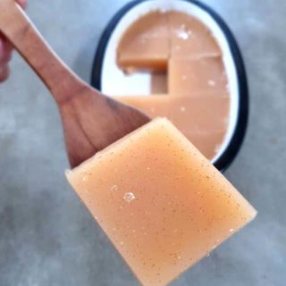 A slice of keto gelatin being help up with a wooden spoon.