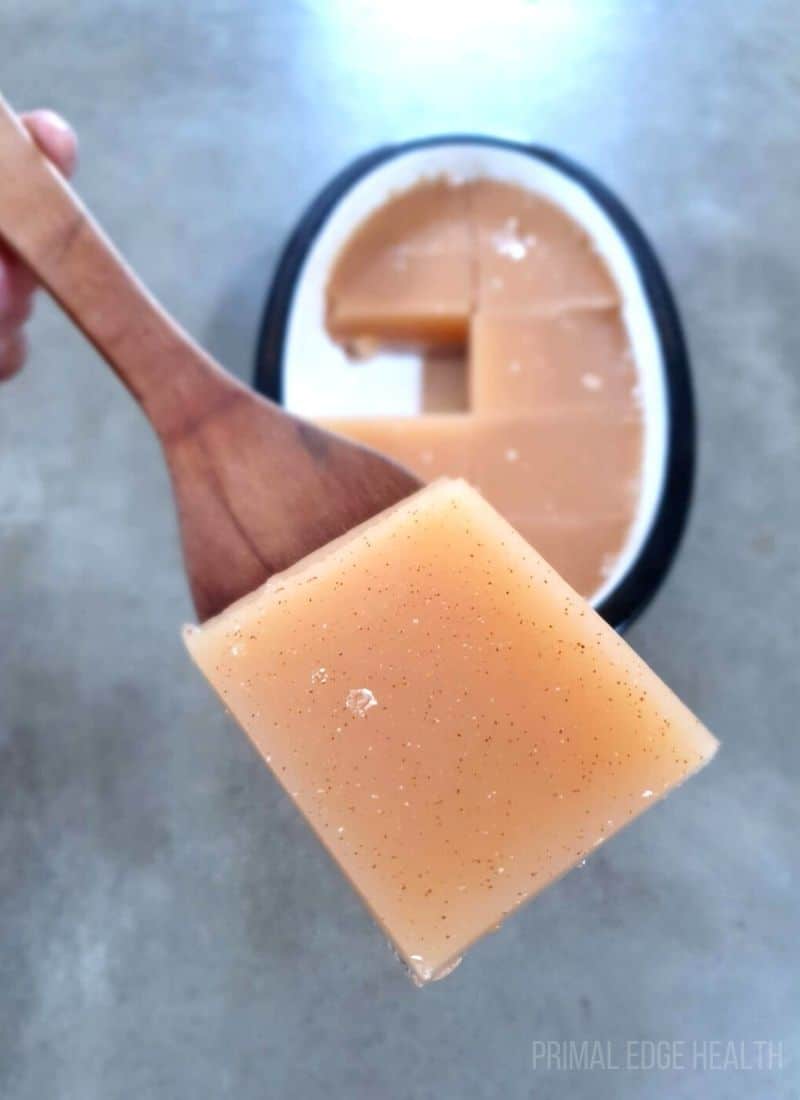A slice of keto gelatin being help up with a wooden spoon.