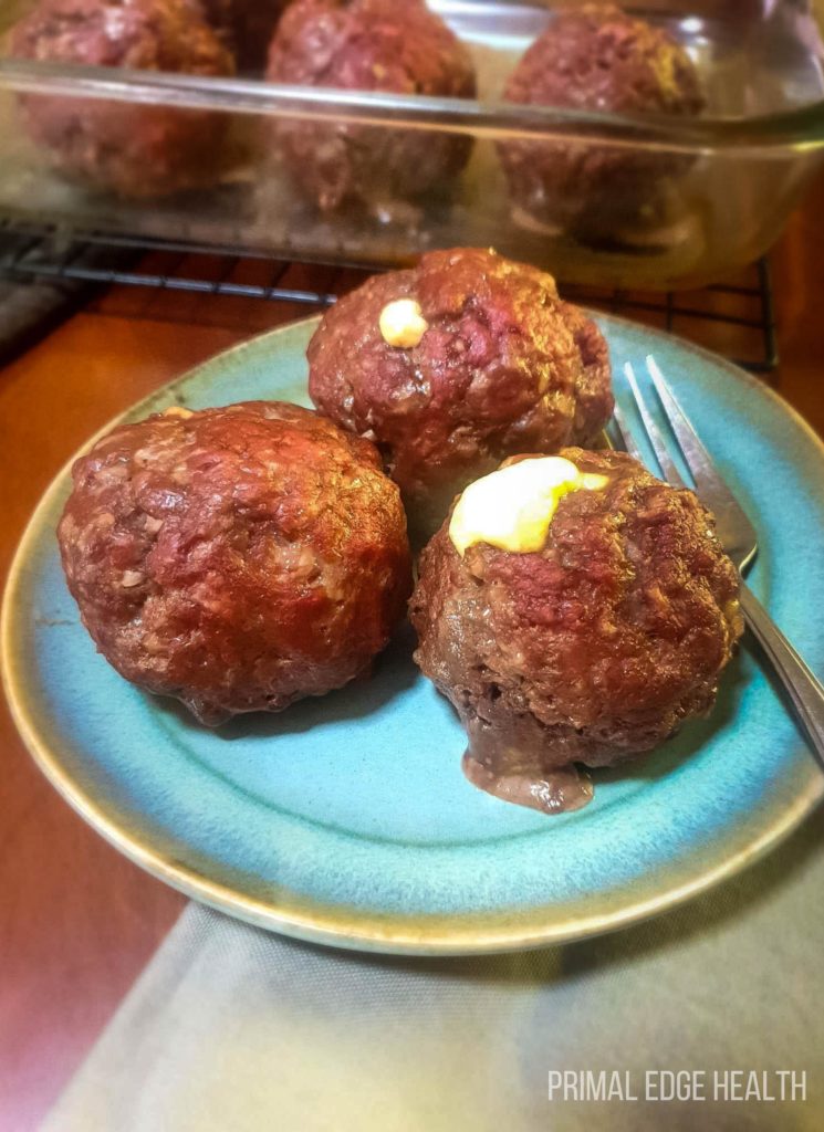 3 pieces of mozzarella stuffed meatballs on a blue plate.