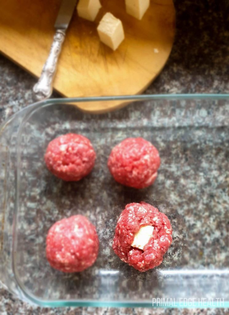 4 pieces of mozzarella stuffed meatballs in a glass dish.