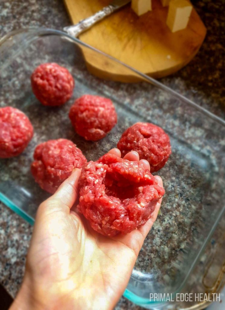 Meatballs in a glass dish with a person's hand holding one up.