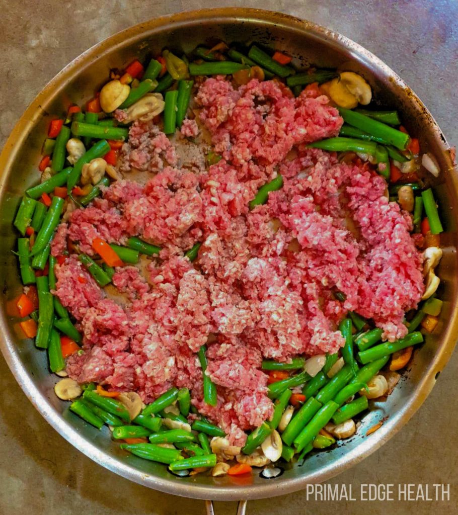 Raw ground beef and vegetables in a bow.