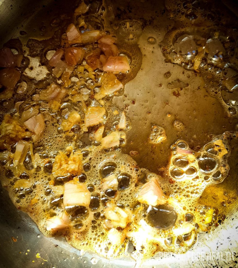 Oil and garnish being cooked in a pan.