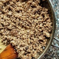 Ground beef in a pan with a wooden spoon.