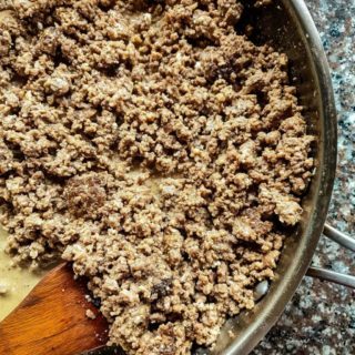 Ground beef in a pan with a wooden spoon.