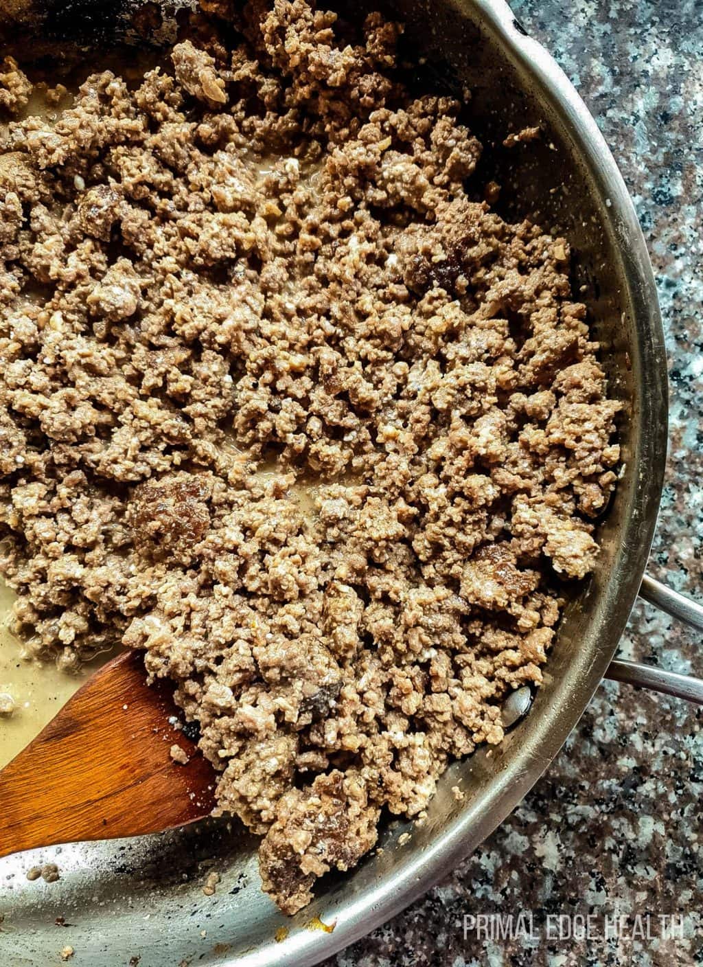 Ground beef in a pan with a wooden spoon.