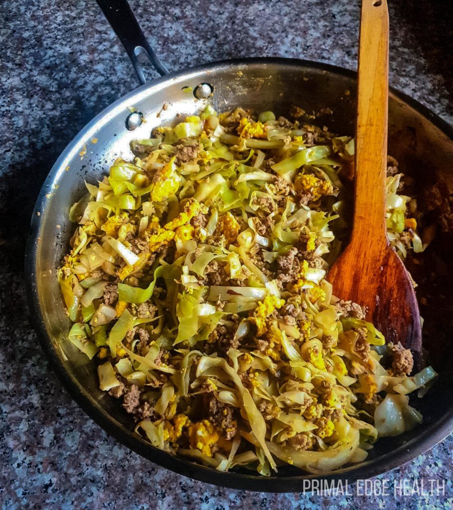 Egg roll in bowl with a wooden spoon on a grey surface.