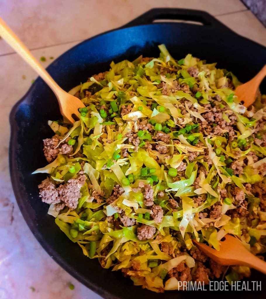 Ground beef cabbage stir fry in a pan with wooden forks.