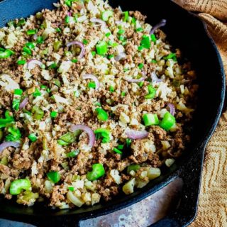 Dirty rice in a pan with a brown cloth.