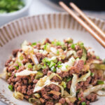 A bowl of stir-fried minced meat with chopped green onions and cabbage.