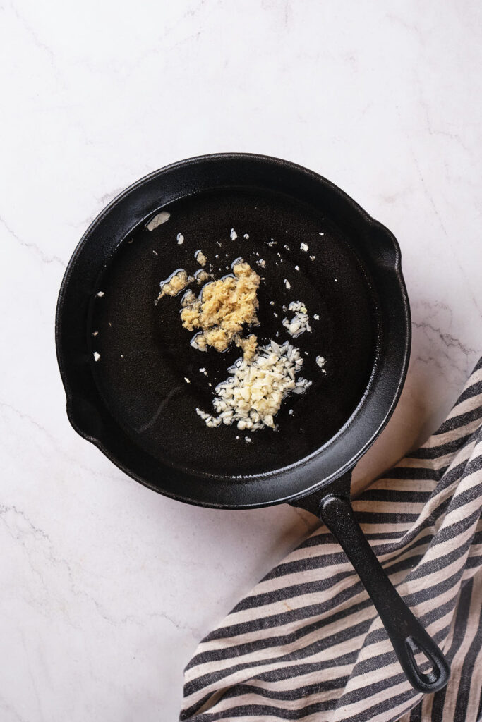 A black cast iron skillet with cabbage stir fry on a striped cloth.