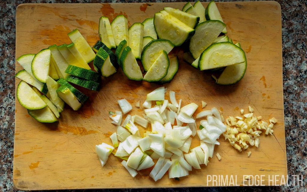 Vegetables and garnishes cut up on a wooden board.