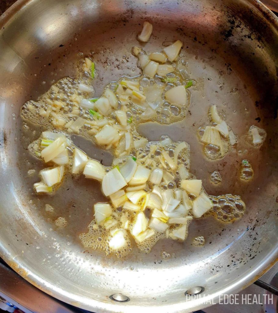 Onions being sauted in a pan.