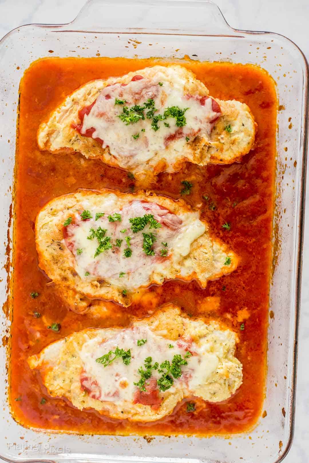 Keto Baked Chicken Parmesan in a glass dish.
