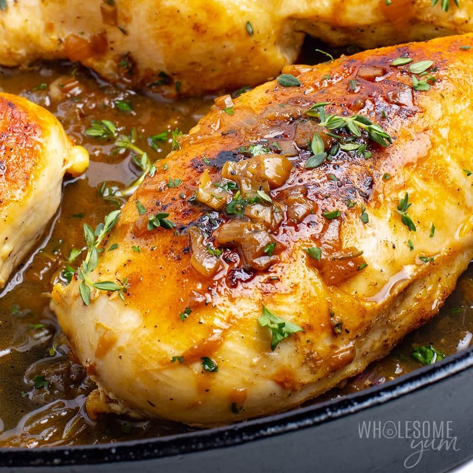 Pan seared chicken breast on a black plate.