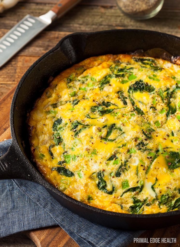 A pot of easy keto frittata on a wooden board with a blue cloth.
