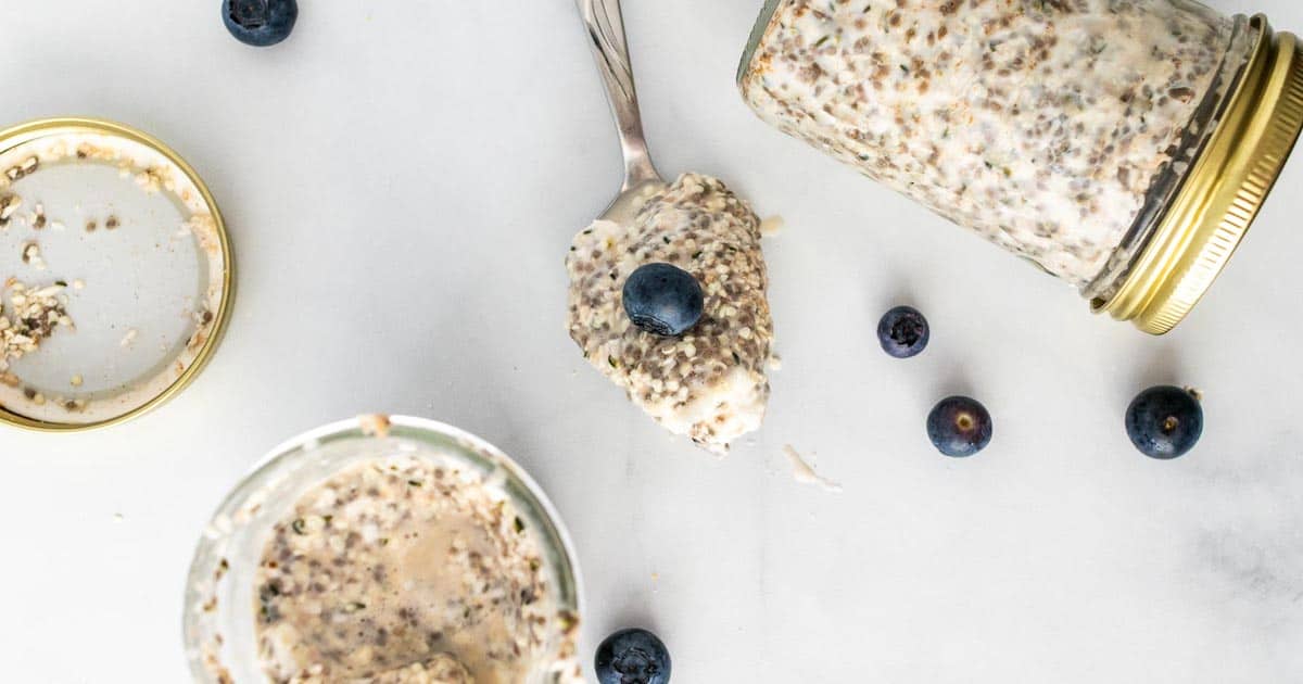 A jar and a spoonful of to overnight oats on a white surface.