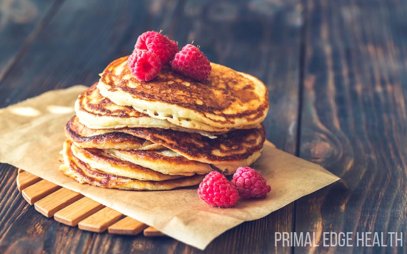 A stack of pancakes garnished with raspberries.