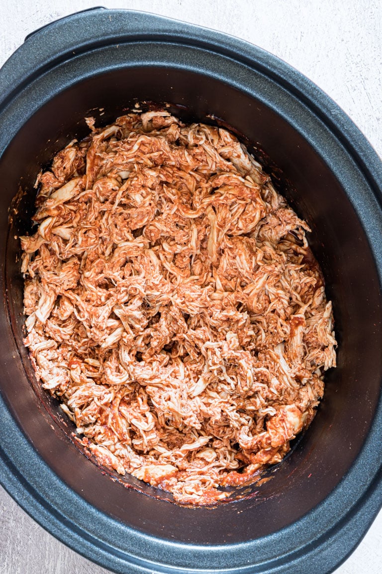 Crockpot salsa chicken in a black pot.