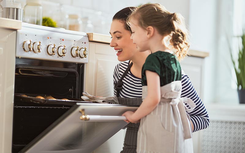 A woman and a child peeking into an oven.