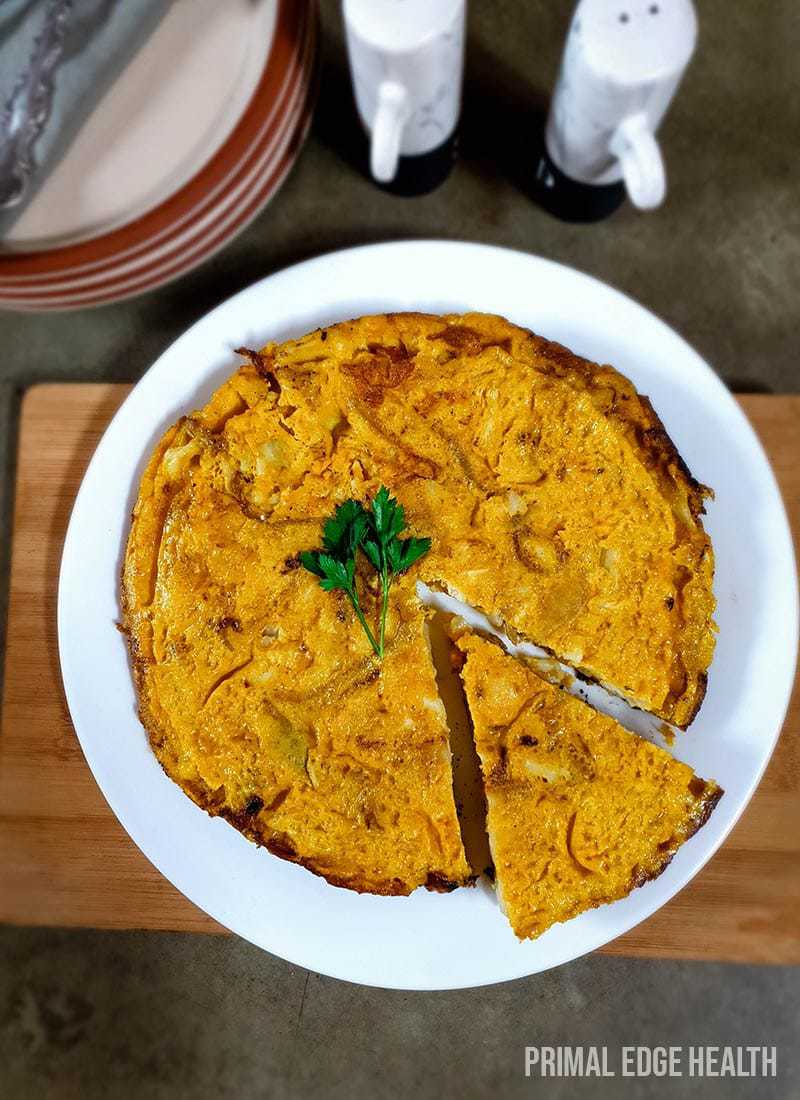 Spanish omelette one a white plate over a wooden board.