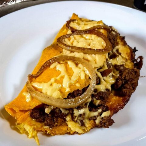 Omelette with meat on a plate garnished with onions.