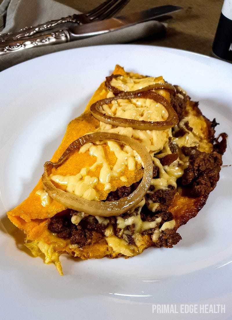 Omelette with meat on a plate garnished with onions.