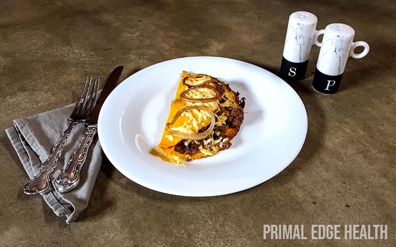 Hamburger omelette on a white plate served with fork and knife.