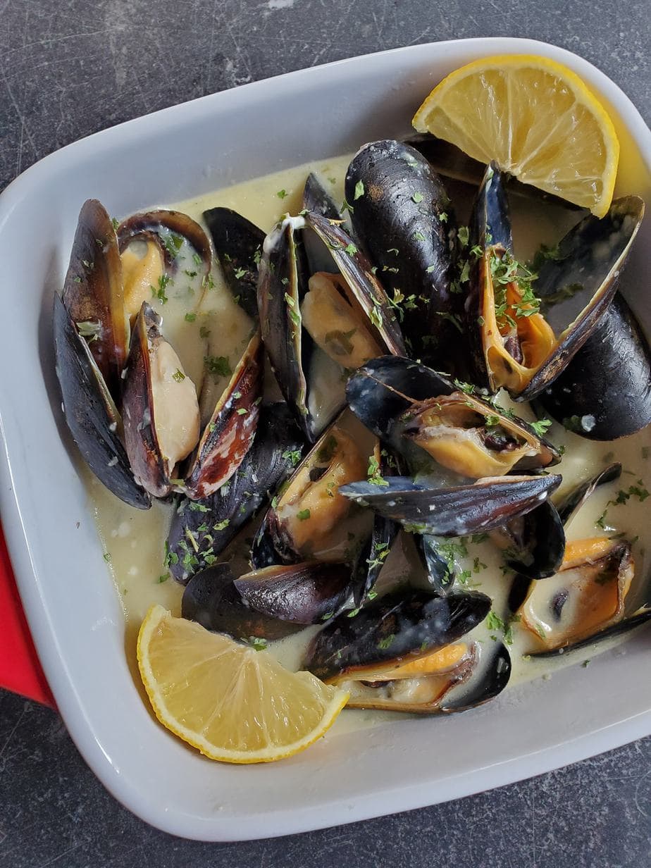 Mussels with lemon slices in a square plate.